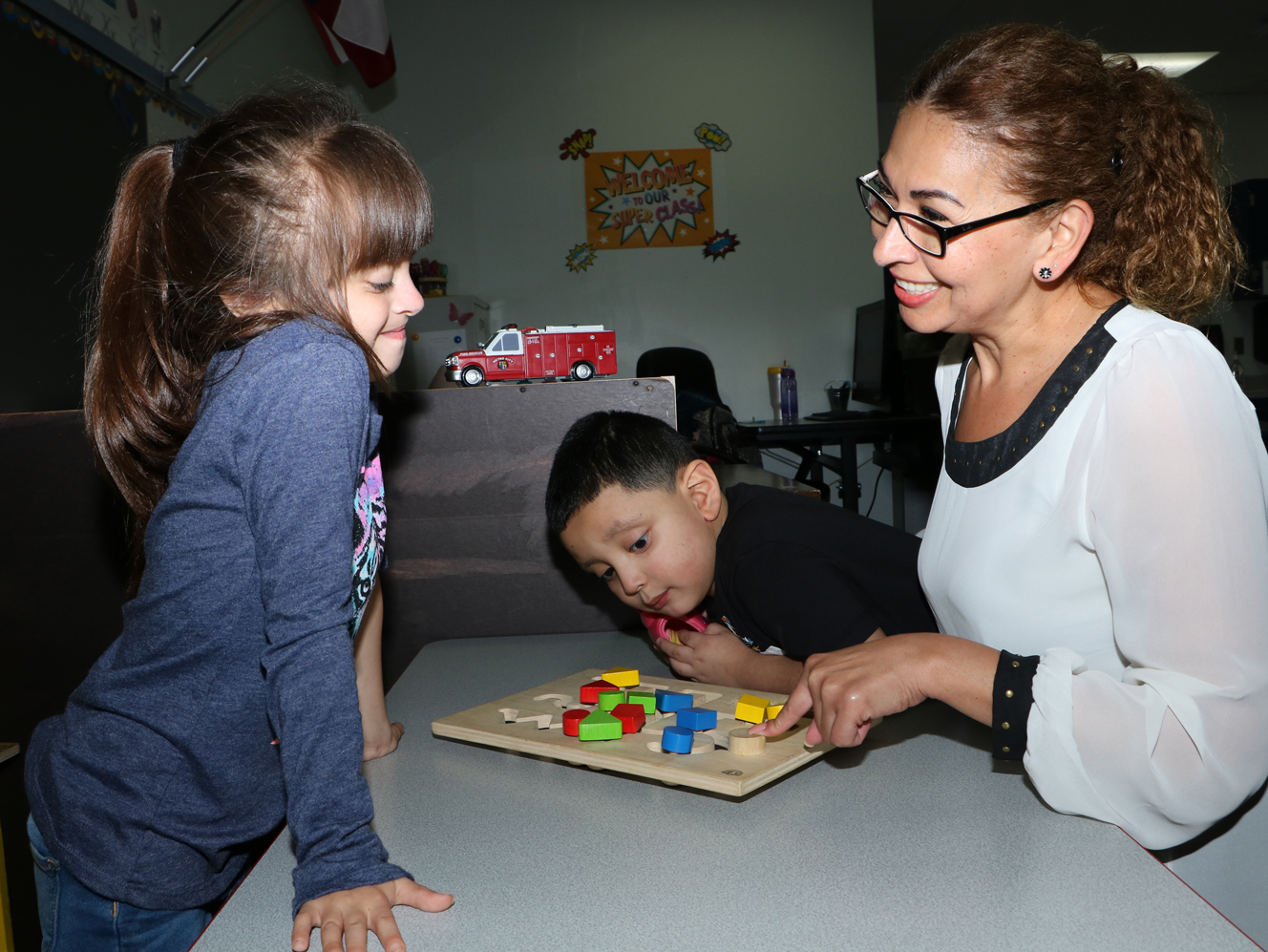 
Silvia Miranda-Villegas helps students Kendallyn Saucedo (left) and Andrew Rodriguez learn their shapes as she works as an instructional aide in Jennifer Owens’ classroom at Carver Elementary.
