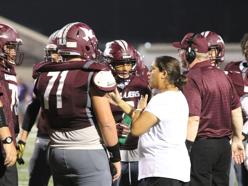 
Coach Tim Finn (right), athletic coordinator and head football coach for the Robert E. Lee High School Ganders, calls a play as Leticia Arredondo, deaf ed interpreter, signs for Billy Haynes (left).
