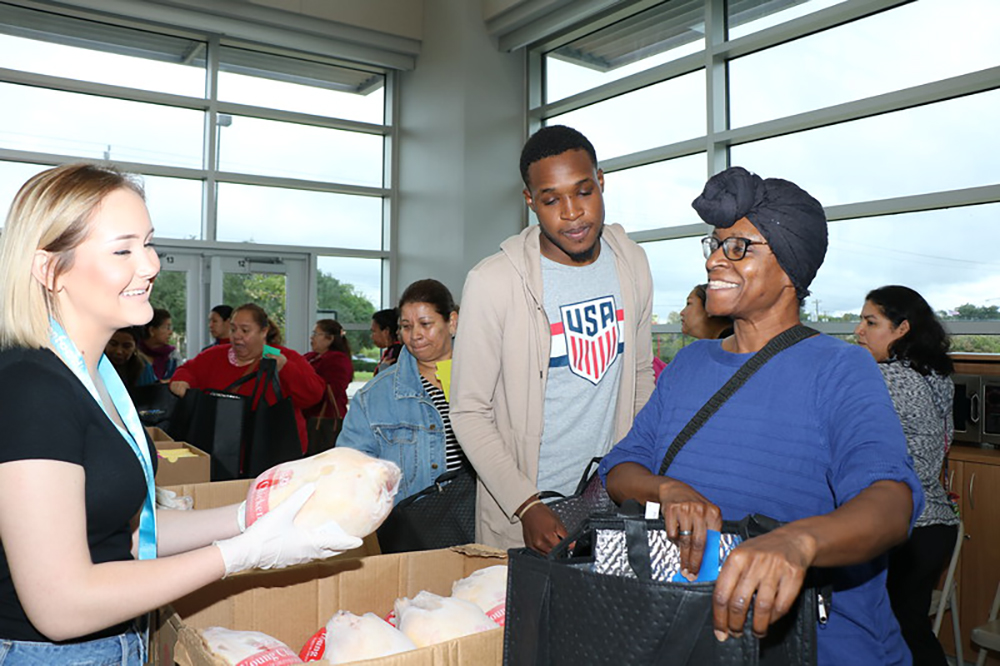 
Brittney Norton (left), a junior at IMPACT ECHS, helps Michelle Preston (right), a student at Lee College, and her son Jamaska Marion select a frozen chicken at the Spartan Market, held at IMPACT in coordination with the Houston Food Bank.
