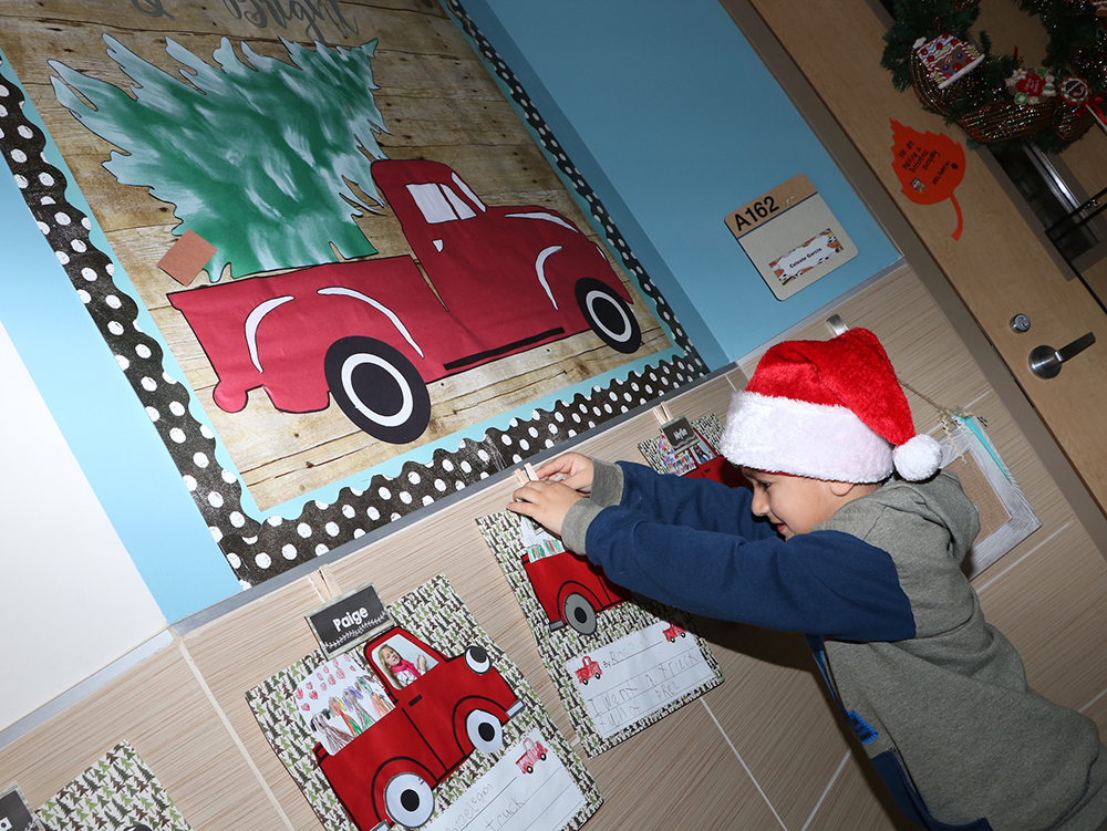 
Rocco Ochoa, a kindergarten student at Bañuelos Elementary, hangs his Truckload of Toys project outside Celeste Garcia’s classroom.
