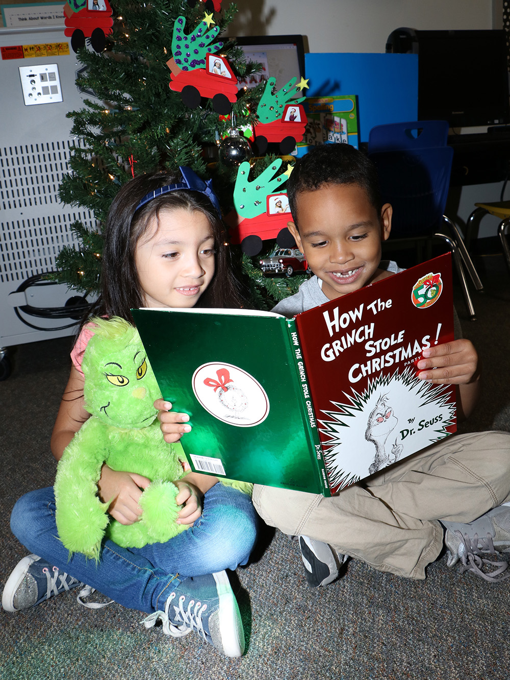 
Kindergarteners from Bañuelos Elementary Athena Santos (left) and Jordan Rodriguez-Rivera (right) enjoy reading the book, “How the Grinch Stole Christmas,” by Dr. Seuss.
