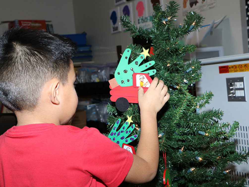 
Alex Tejeda, a kindergarten student in Celeste Garcia’s class at Bañuelos Elementary, hangs his special ornament on the Christmas tree.
