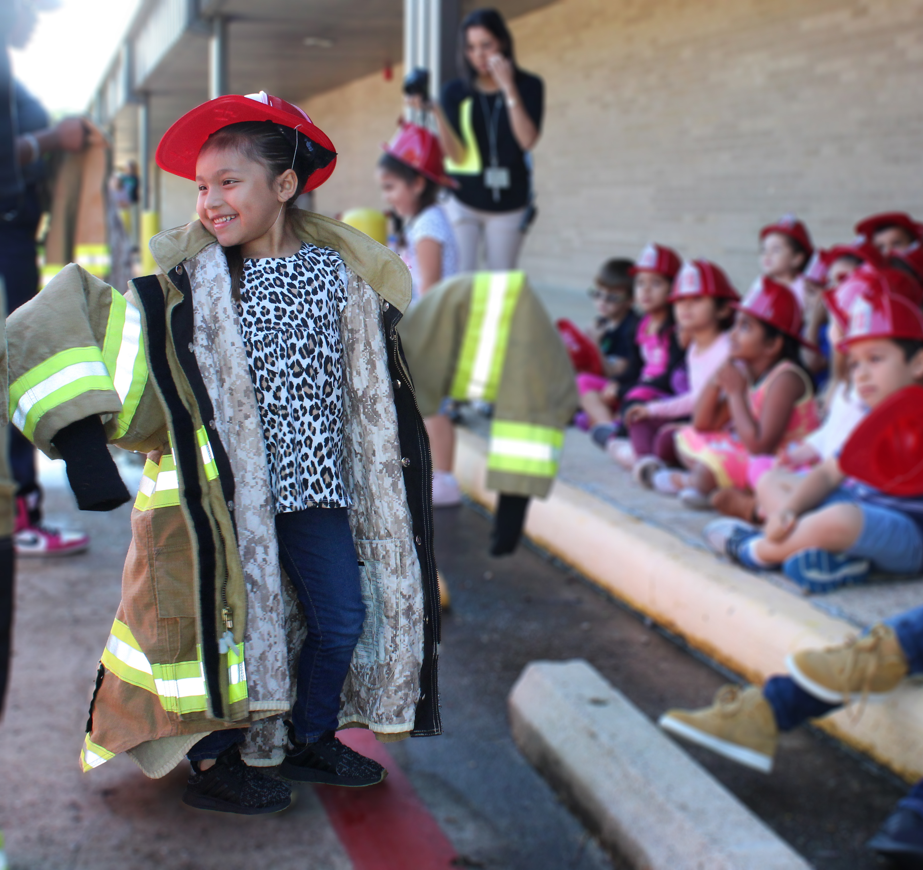 
Aliyah Rodriguez, a kindergarten student at Crockett Elementary, tries on a firefighter jacket provided by Chevron Phillips Chemical volunteers during Fire Prevention Week.
