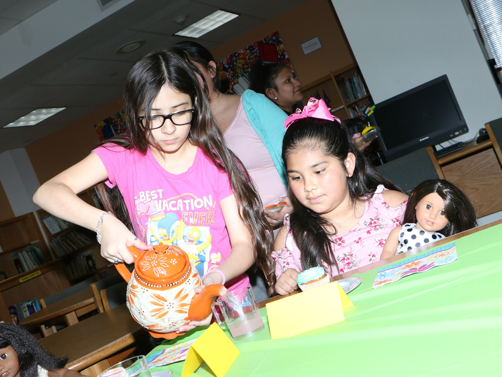 
Brianna Chavez and Giselle Del Toro enjoy lemonade and cupcakes at the tea party in the Ashbel Smith Library after receiving dolls from Dolls4All.
