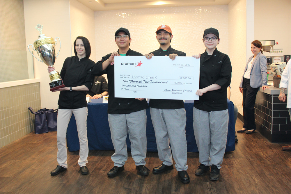 
Chef Kylie Sobczak (left), coach of the Goose Creek CISD Culinary Arts team from Stuart Career Tech High School, proudly holds the first-place trophy her students (from left) Alejandro Alcantar, Nathan Garza and Destiny Whitener, won in Aramark’s 2019 Lone Star Chef state contest at Minute Maid Park. The three also won $2,500 in scholarship money.
