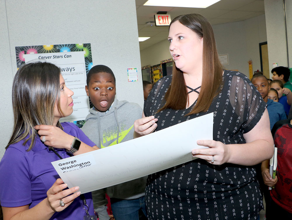 
Christine Hunter, a teacher at Carver Elementary, receives a grant from Erika Foster, Goose Creek CISD Education Foundation director, while Carver student Demerick Taylor reacts to seeing the check.
