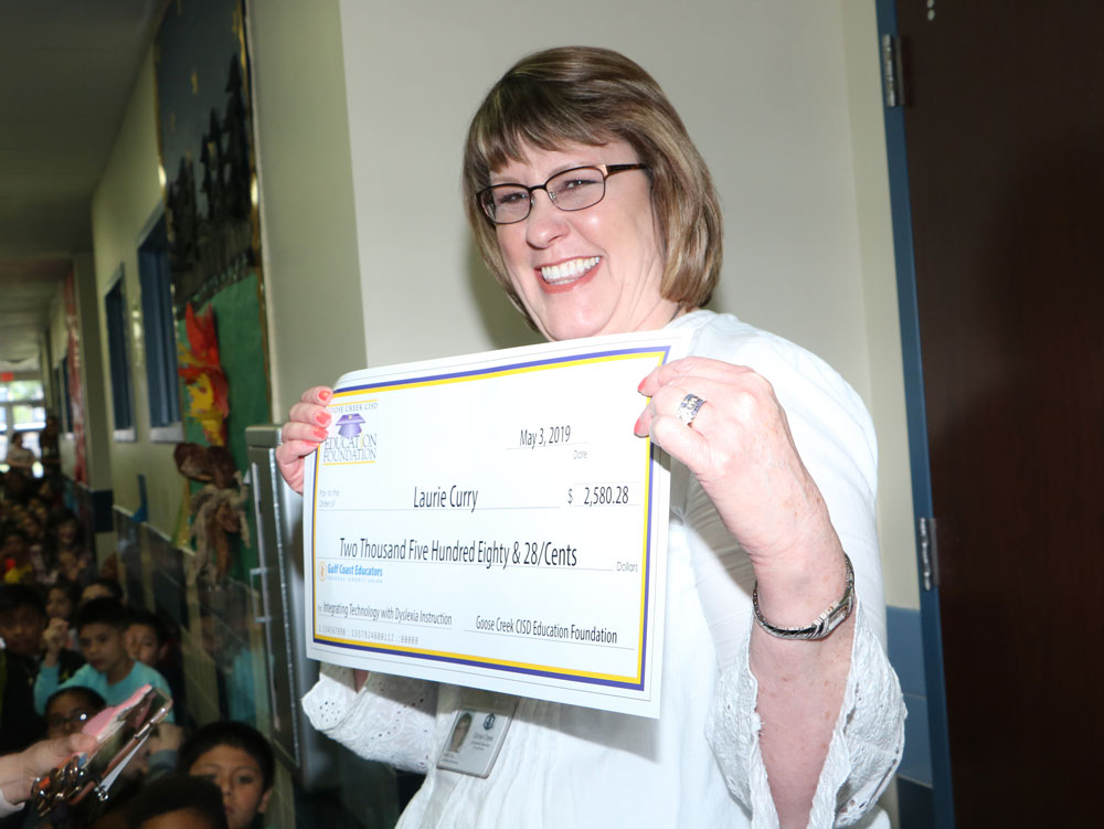 
Laurie Curry, a teacher at Bowie Elementary, shows off the check for her grant for $2,580.28 for “Integrating Technology with Dyslexia Instruction,”  presented to her by the Goose Creek CISD Education Foundation’s Grant Surprise Patrol.
