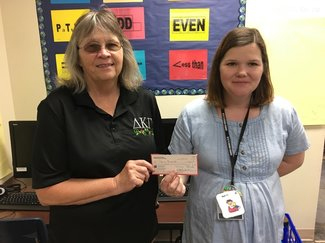  Karen Stephens from the Gamma Nu chapter of Delta Kappa Gamma Society International, presents a Grants-In-Aid check to Donna Alexander, a first-grade teacher at Bowie Elementary. 