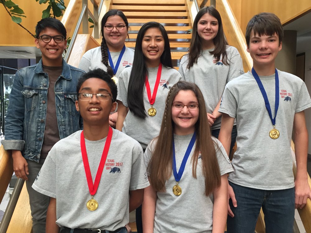 Seen students stand infant of stairway with medals. They are heading to national completion for History Day. 
