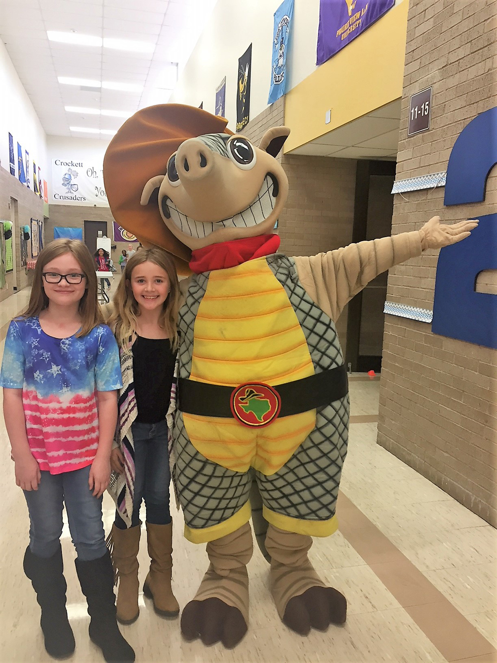  (from left) Katelyn Brasfield and Delaney Truesdale meet Andy the Armadillo from Texas Roadhouse during Crockett Elementary’s Camp Read-A-Lot Family Night to promote reading at home. Texas Roadhouse provided bookmarks for students, who will earn a free meal after they read three books. Staff members also enjoyed delicious rolls from the restaurant.  
