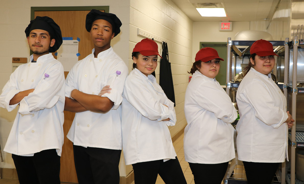  Ross S. Sterling High School’s chef team of (from left) Brayan Franco and Haylon Haynes, coached by Alesha Tate, wait for the results of their cook-off with Robert E. Lee High School’s chef team of Naomi Carney, Mildreth Sandate and Darely Sandate, coached by Ginger Zoidis during the recent Latin Fusion – Lone Star Chef Competition at Stuart Career Tech High School. 