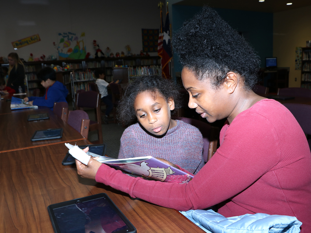 
Gahla Osman, a second-grader at Alamo Elementary, enjoys reading to her mother Alesha Tate during Alamo Fitness Frenzy. Hosted by the Baytown YMCA and Aramark, the event encouraged families to participate in fitness activities, eat healthy snacks and exercise their brains by reading.
