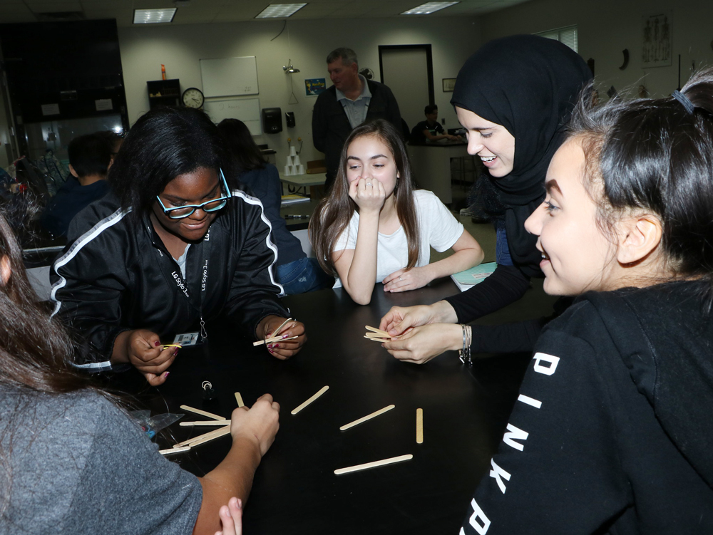  Danielle Gore, (second from right), a chemical engineer at Chevron Phillips Chemical, laughs with  Gentry students (from left) Jordan Phillip, Lana Larrabee and Alayna Harville as they use teamwork to build a catapult. 