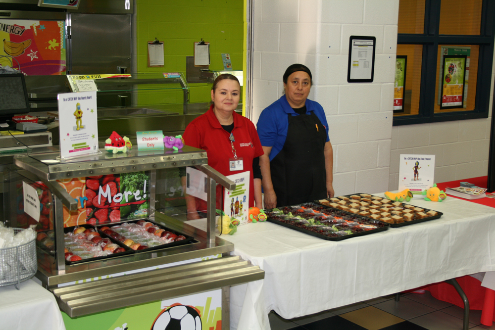 Two food services workers prepare snacks