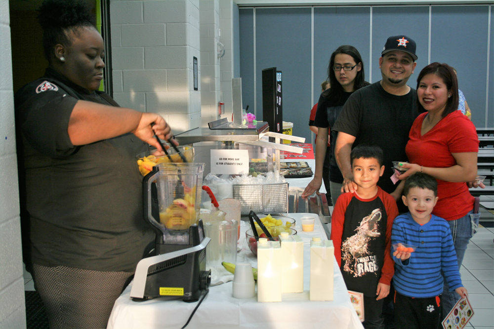 Carlos Zamora, Jr. and Christopher Zamora, students at Carver, and their parents Carlos Zamora and Iris Zamora enjoy smoothies provided by Aramark Chef Manager Franchesca Bland at Carver CATCH Family Night