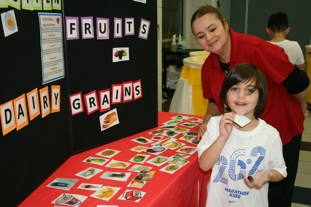 Kurtis Arnold, kindergartener, tests his knowledge of GO SLOW WHOA foods with Alma Cantu, Carver cafeteria manager at Carver CATCH Family Night.