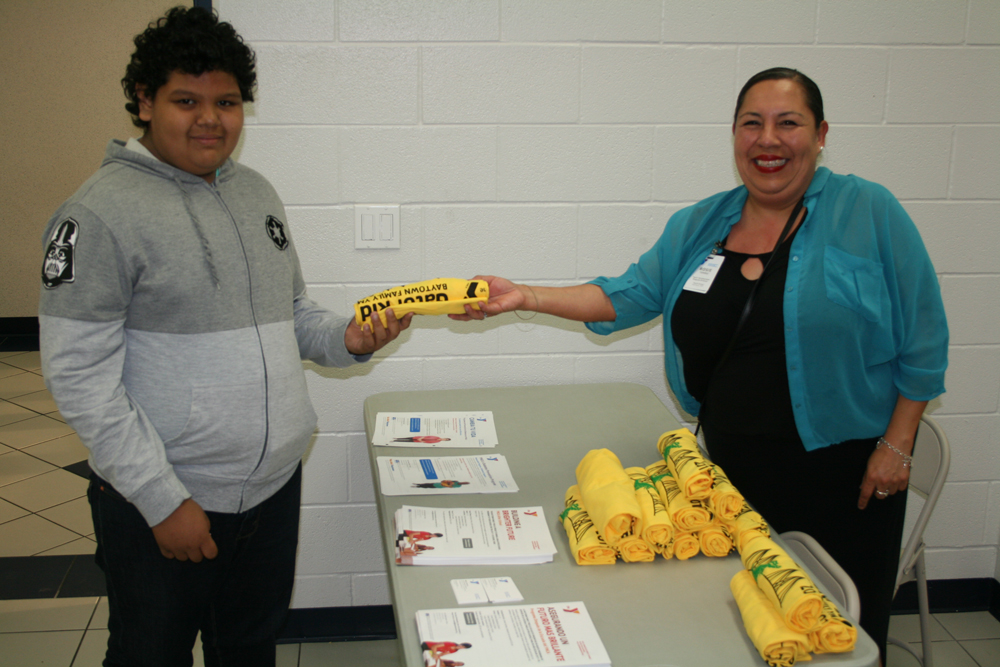 Jose Aguilar, fifth-grader, receives information about the YMCA from Rosie Torrez, YMCA After School Program Coordinator, at Carver CATCH Family Night.