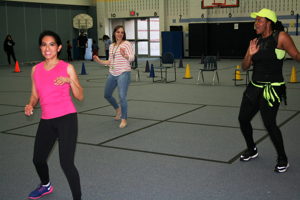 Teachers Courtney Morris (back), pre-k, and Cristina Garcia (front), kindergarten, enjoy Zumba provided by Zumba instructor Coach Reed at Carver CATCH Family Night.
