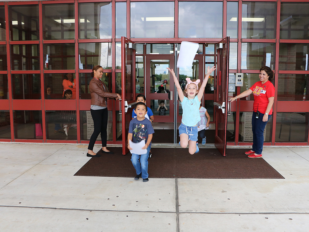 
Celebrating the last day of school are Miguel Magallon, Christian Formoso (back),  Ryliegh Sellman (jumping) and Tania Rodriguez (back). Cyre King and Betty Baca, principal, are holding the doors.
