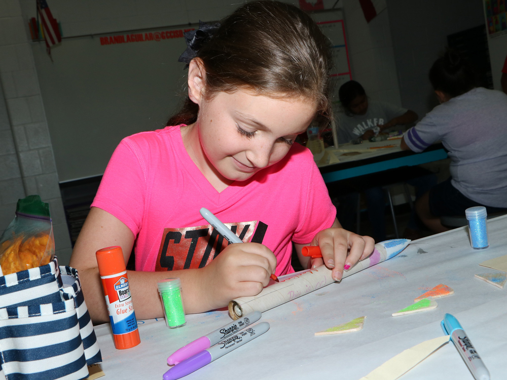 
London Merling, who just finished third grade at Stephen F. Austin Elementary, carefully decorates her rocket at Rocketry Camp at Goose Creek Memorial High School.
