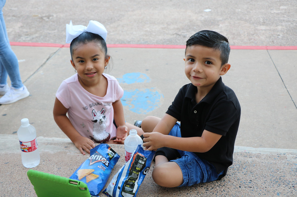 
Aaliyah Pena (left) and Adrian Santos enjoy their snacks as they wait in line at Ross S. Sterling High School to register for pre-kindergarten.
