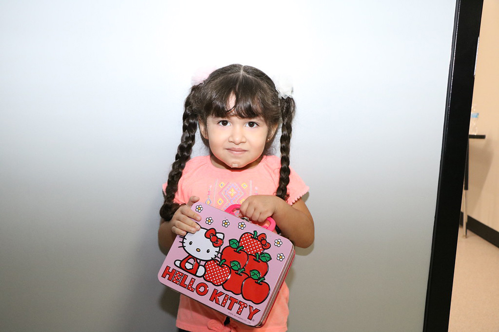 
Barbara Sauceda shows off her new lunch kit as she waits in line at Ross S. Sterling High School to register for pre-kindergarten.
