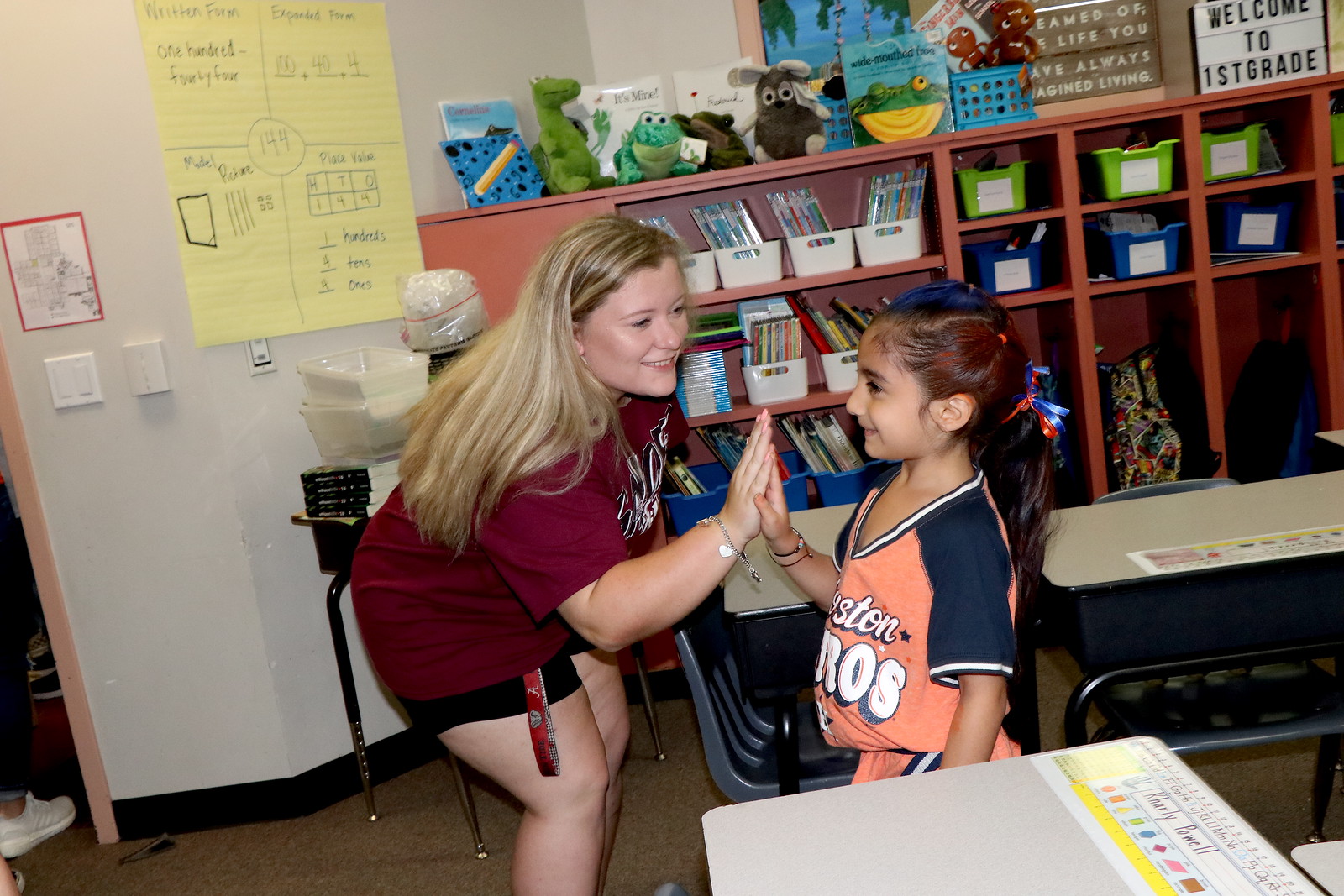 Emmeline Rodriguez (right), first-grader at Travis Elementary, gives a high five to Linzie Jarvis, a Robert E. Lee High School softball player, after winning Biggest Astros Fan in her classroom.