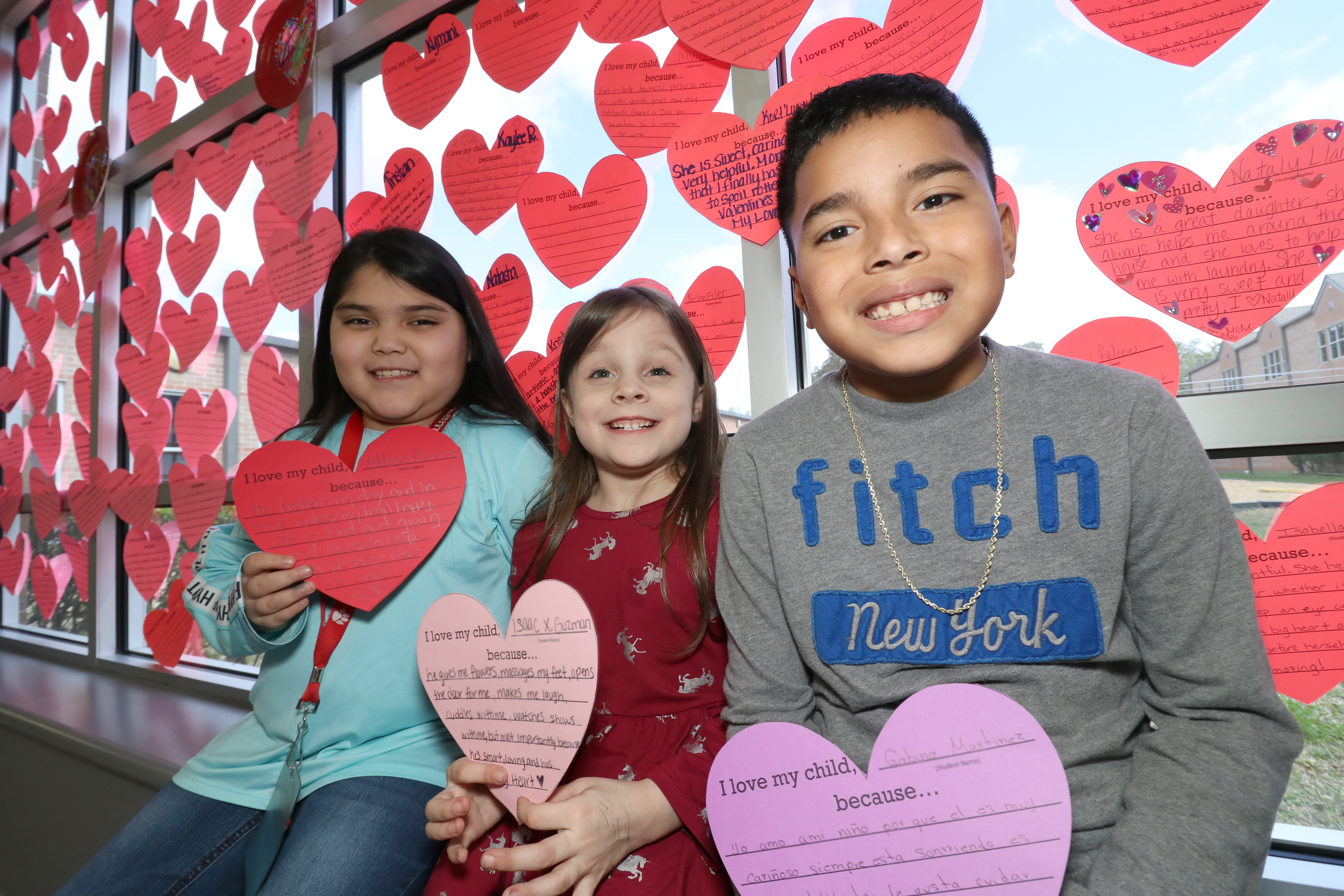 Students pose with hearts with writing from their parents