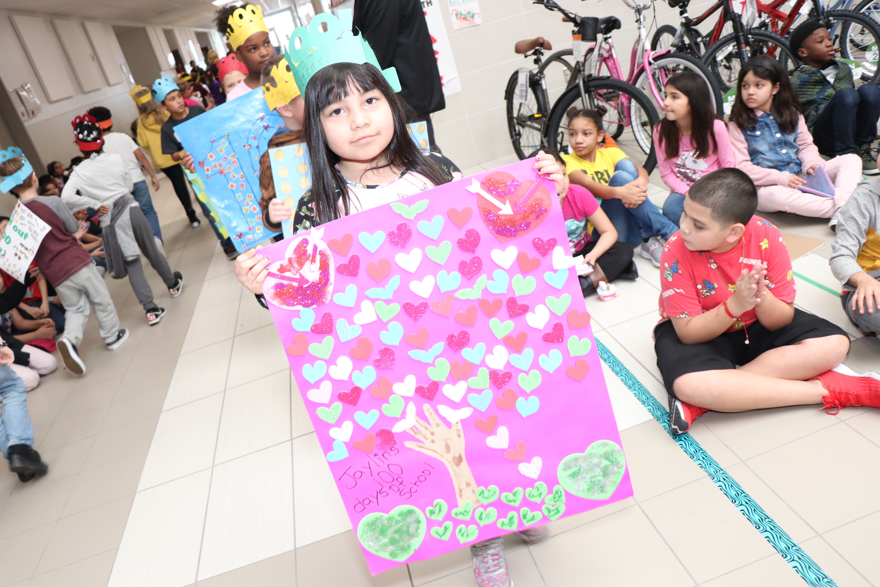 Student holds 100th day tree poster