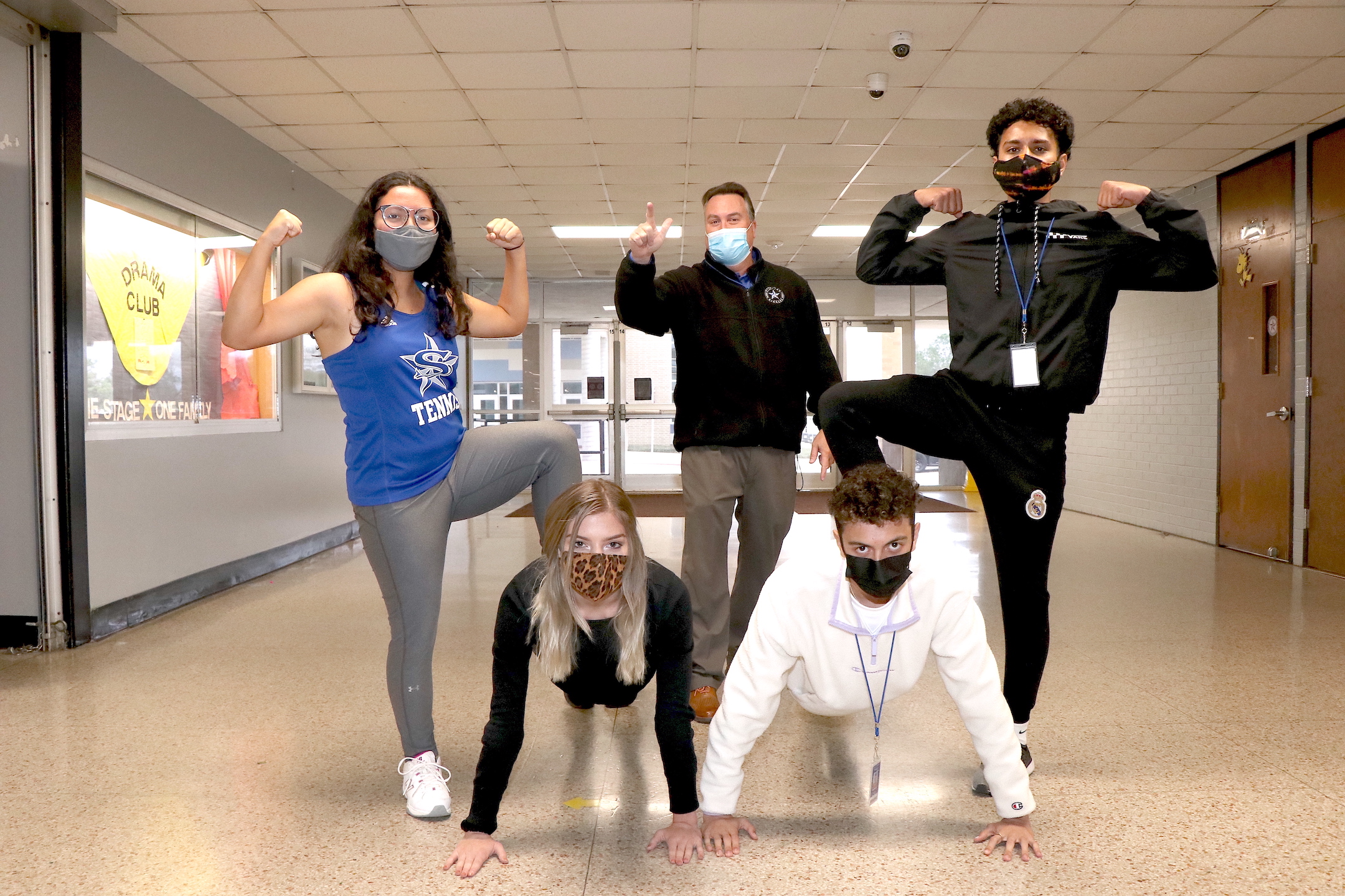 principal and students flexing muscles in running gear