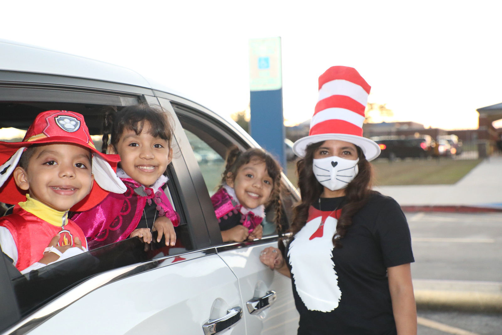 staff stand next to car with students