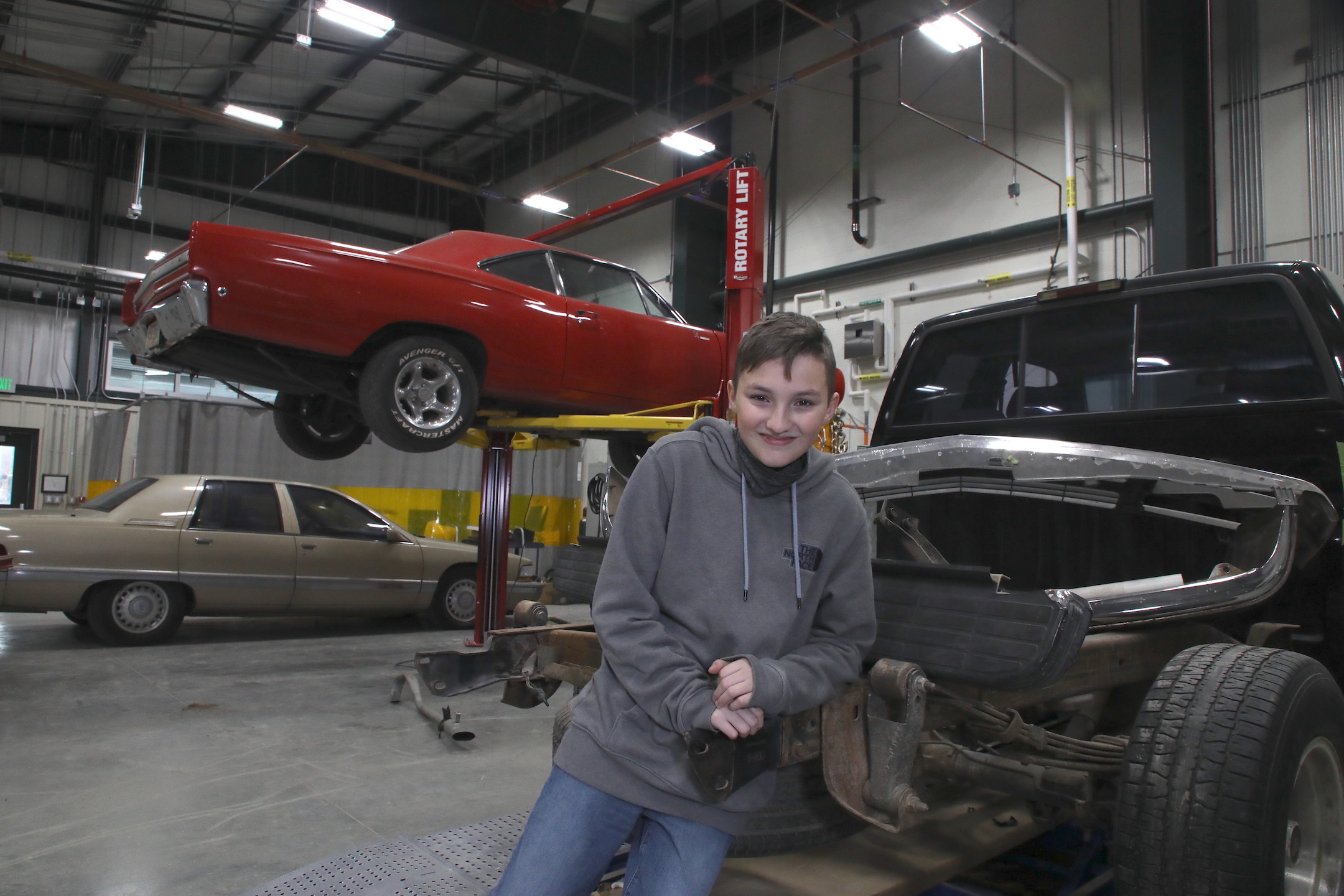 Student leans on a car in auto collision class