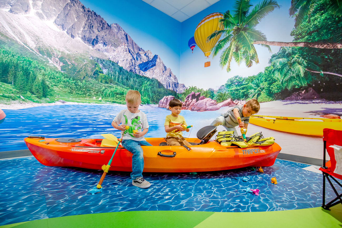 Students play on a kayak in a beach themed room