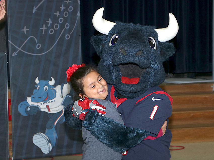 Gabby Ortiz, first-grader at De Zavala Elementary, gets a hug from Toro after telling him he is her favorite Texan during the “Toro Takes the Bull Out of Bullying” program.