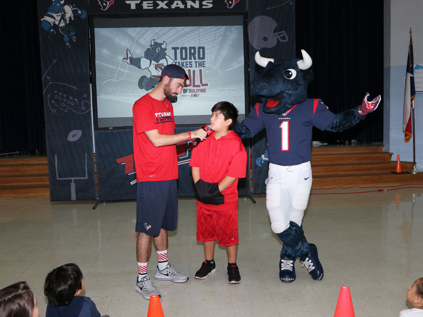 Ryan Records with the Texans Mascot program asks Jason Ramirez, fifth-grader at De Zavala Elementary, a question about bullying during De Zavala Elementary’s “Toro Takes the Bull Out of Bullying” program.