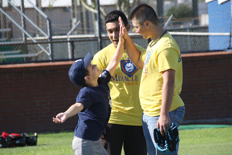 Miracle League member high fives High School Student