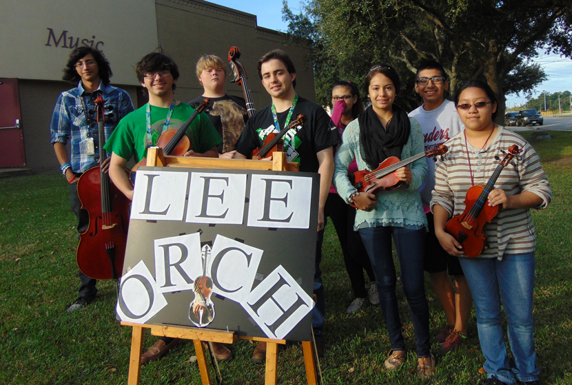 Lee Orchestra students pose in front of sign 