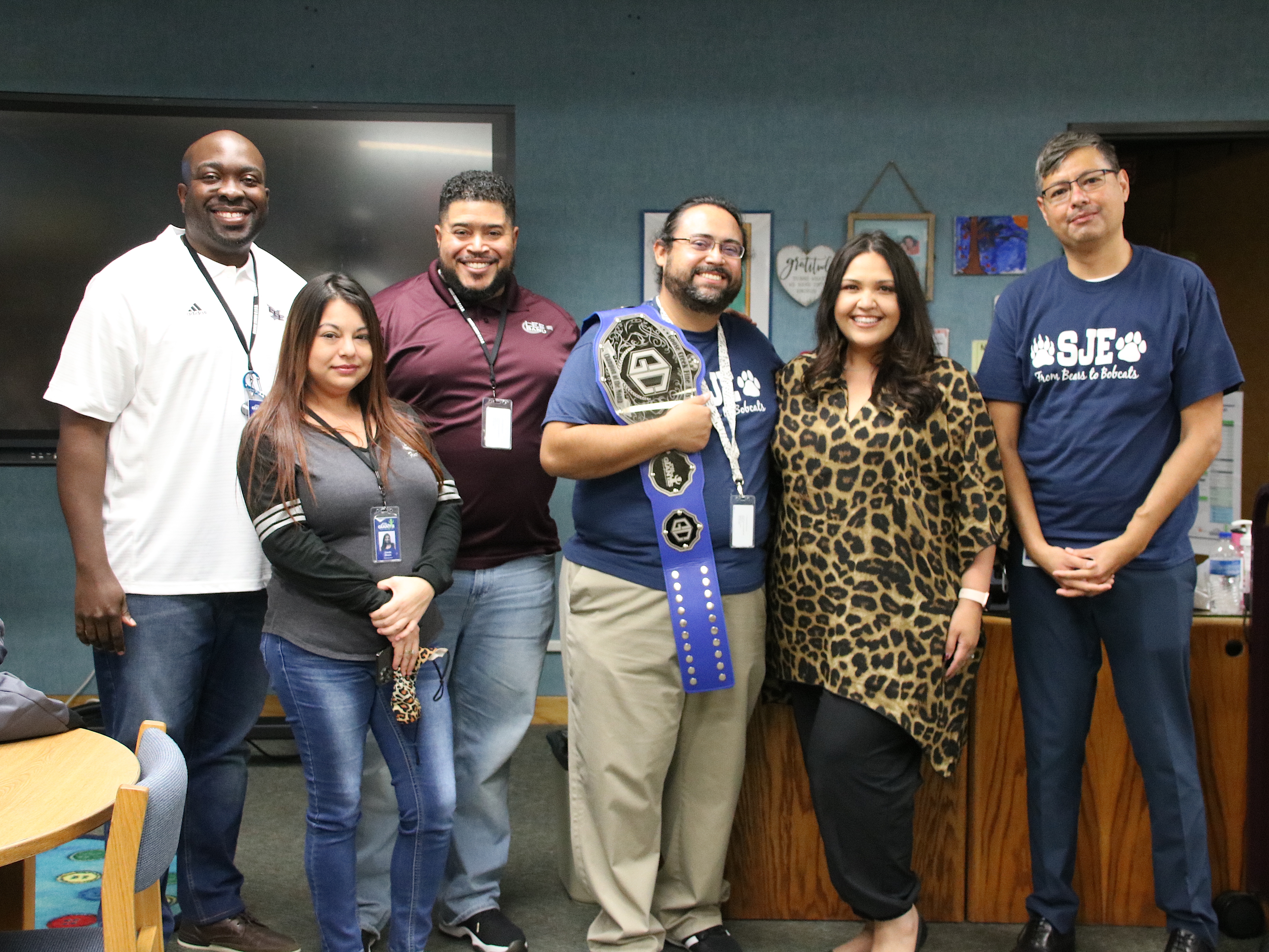 Fine Arts Champion of the Month stands with staff and directors wearing his belt