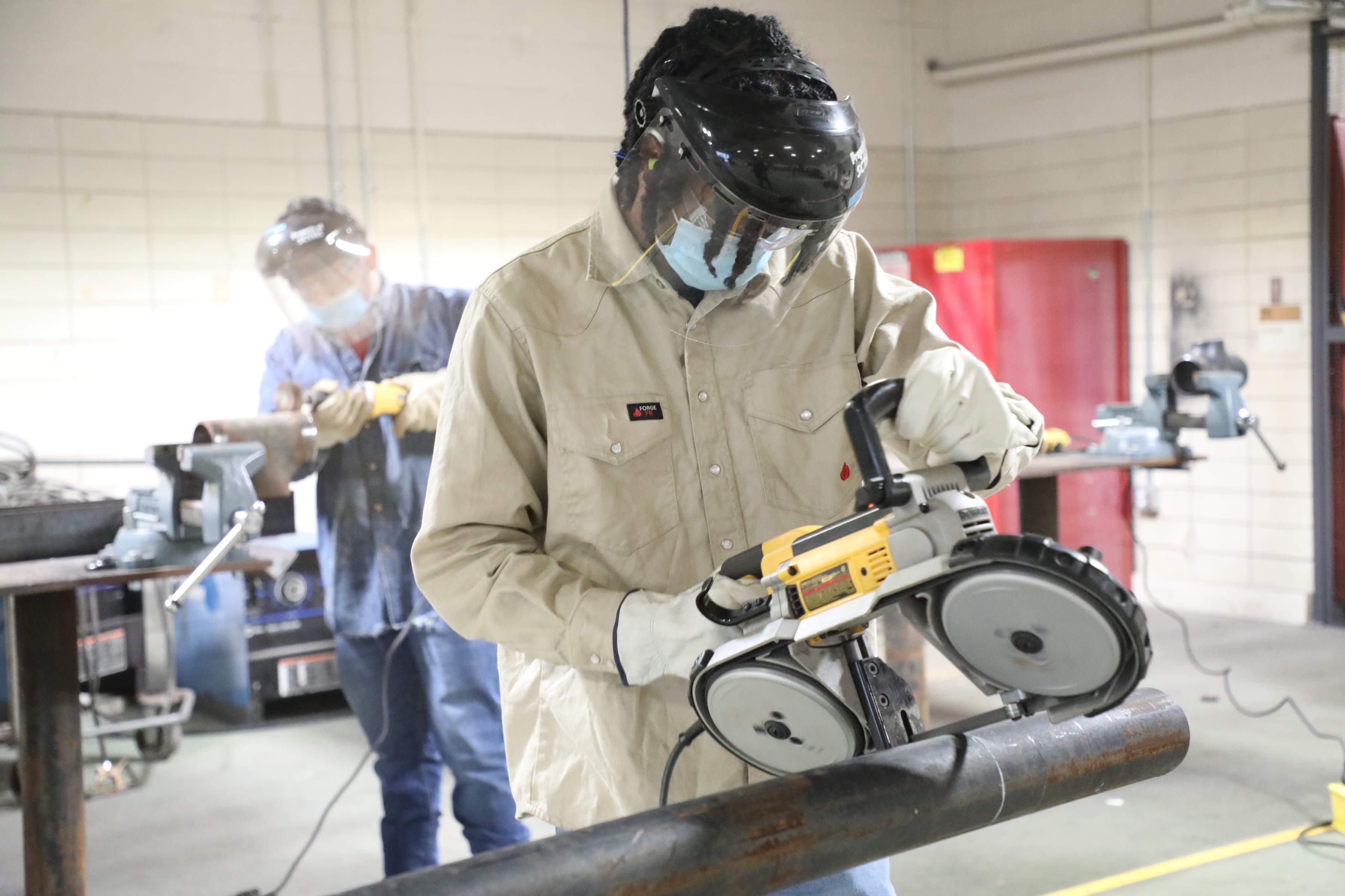 Pipefitting student cutting pipe with a saw