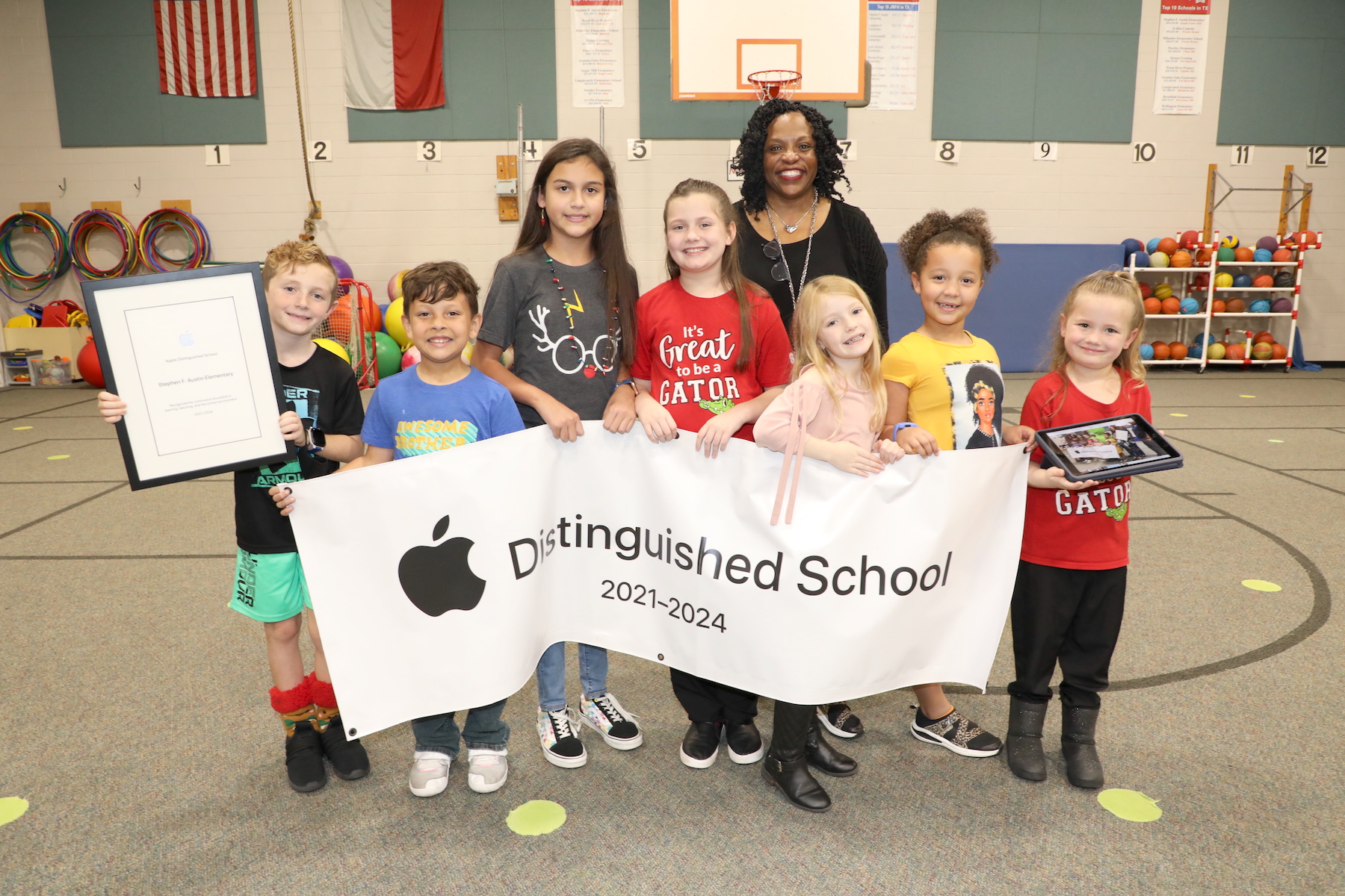 an apple respresentative poses with students holding the Apple Distinguished School banner