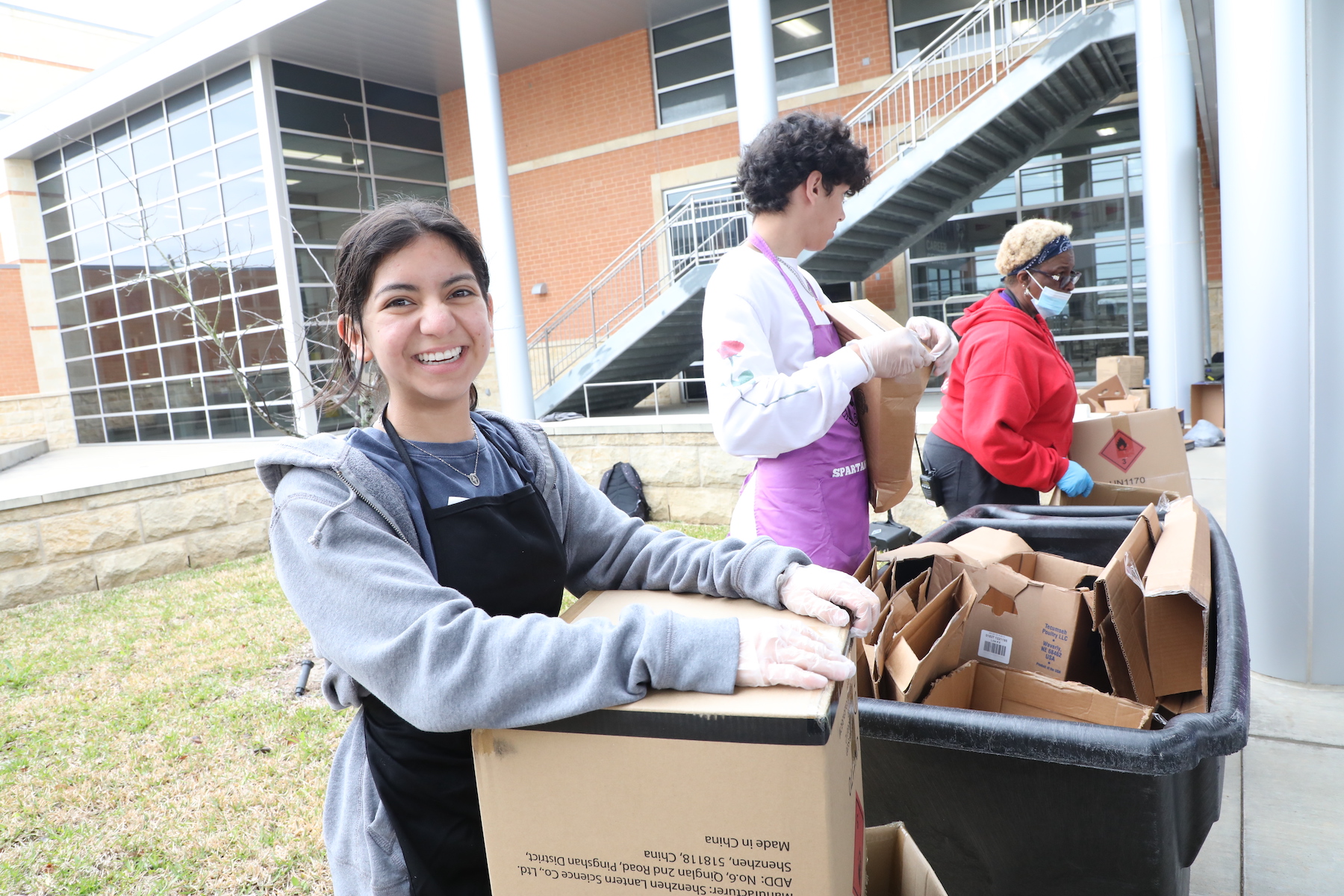 Student helps break down boxes after they are unloaded at the food drive