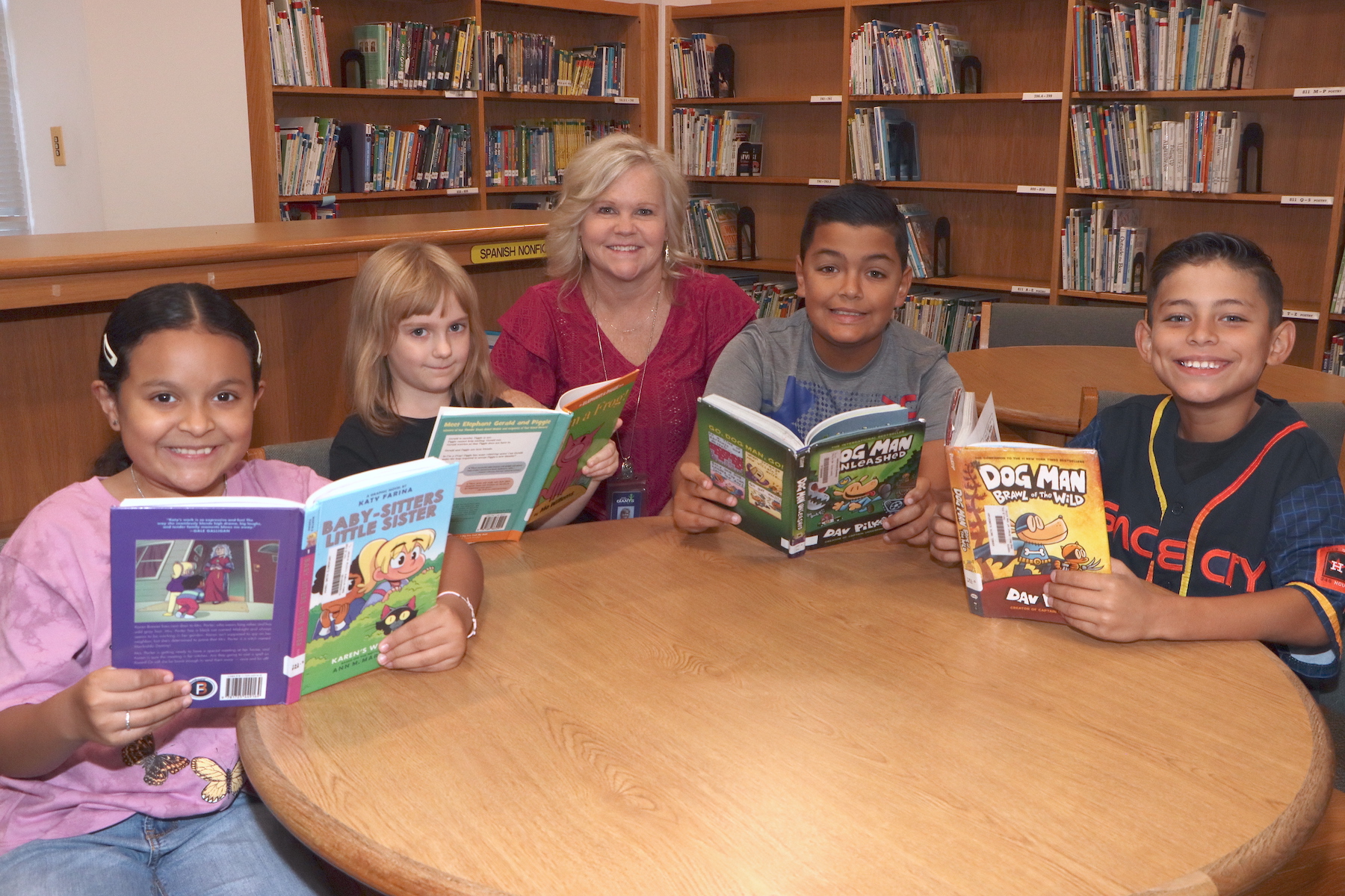Librarian Ramona Townsend sits at table with students holding books