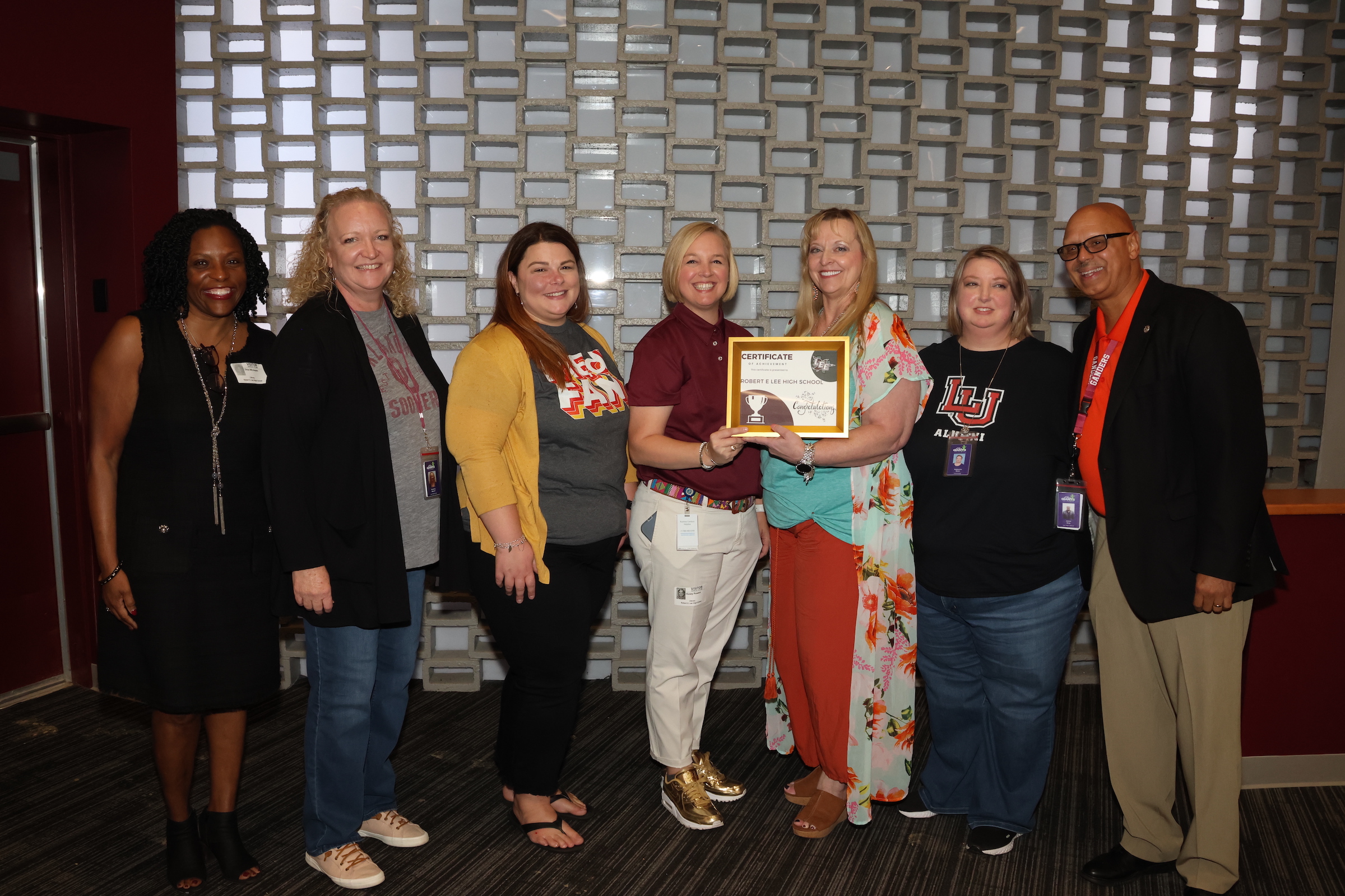 lee high school administrators of members of the technology team post with plaque