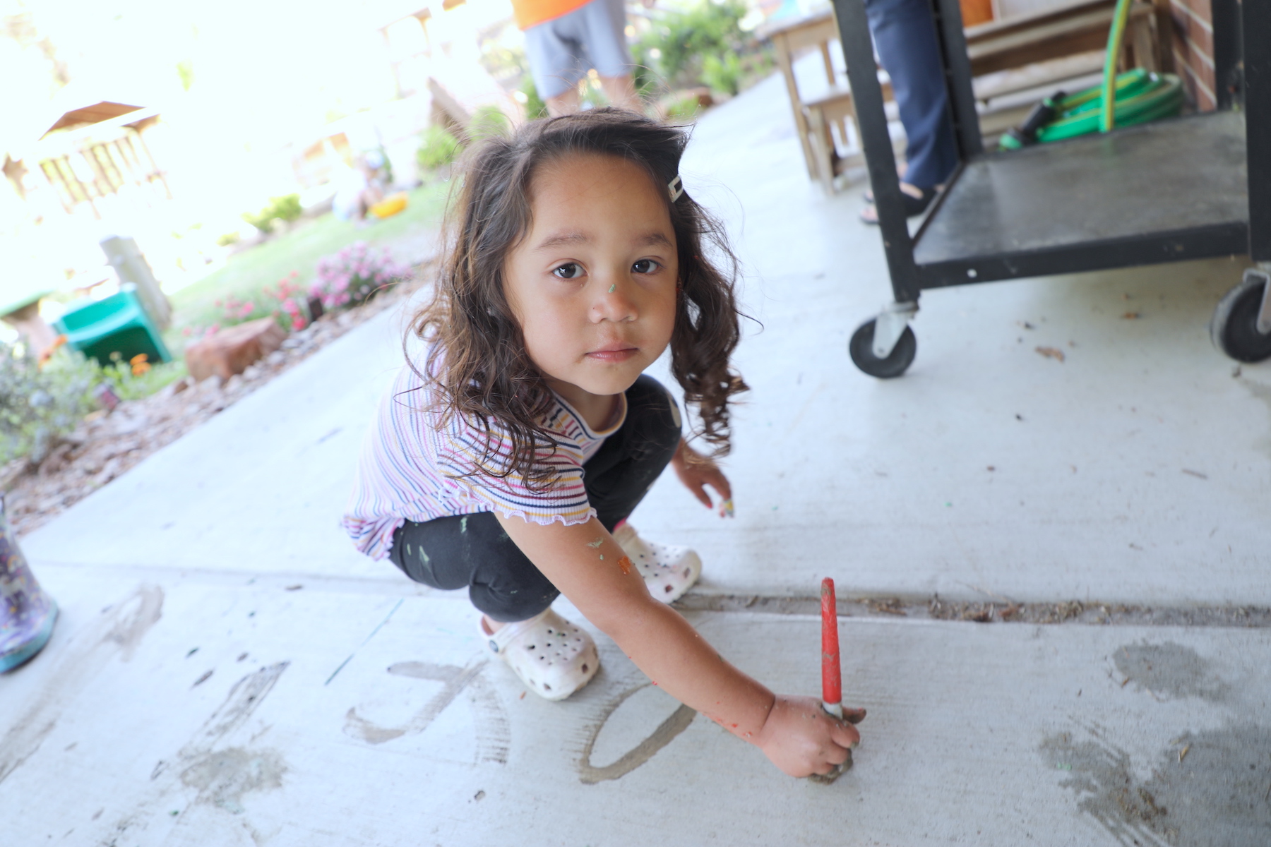 Student paints on concrete walkway and has paint spot on her nose