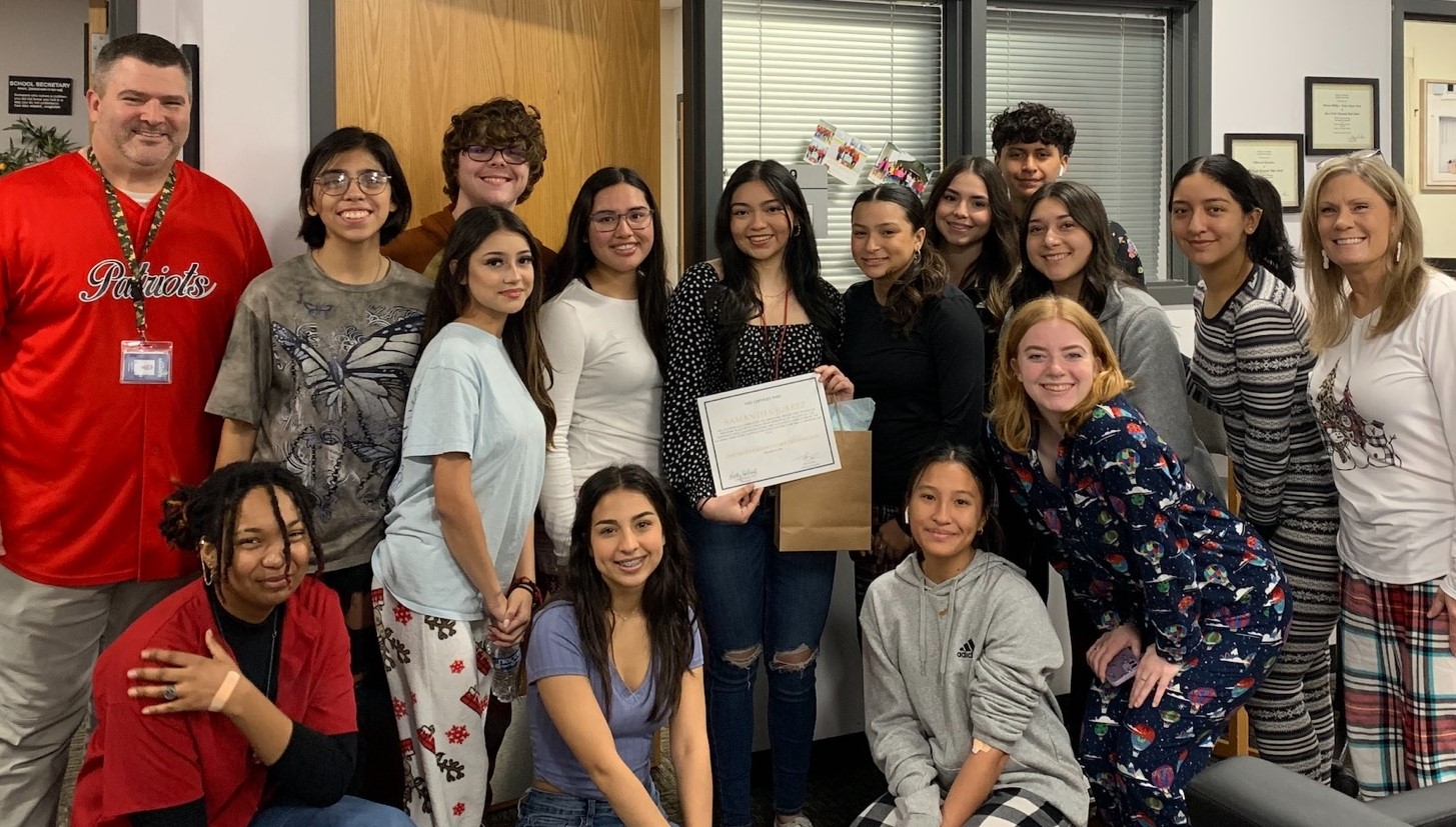 phlebotomy student poses with certification, teacher, and classmates