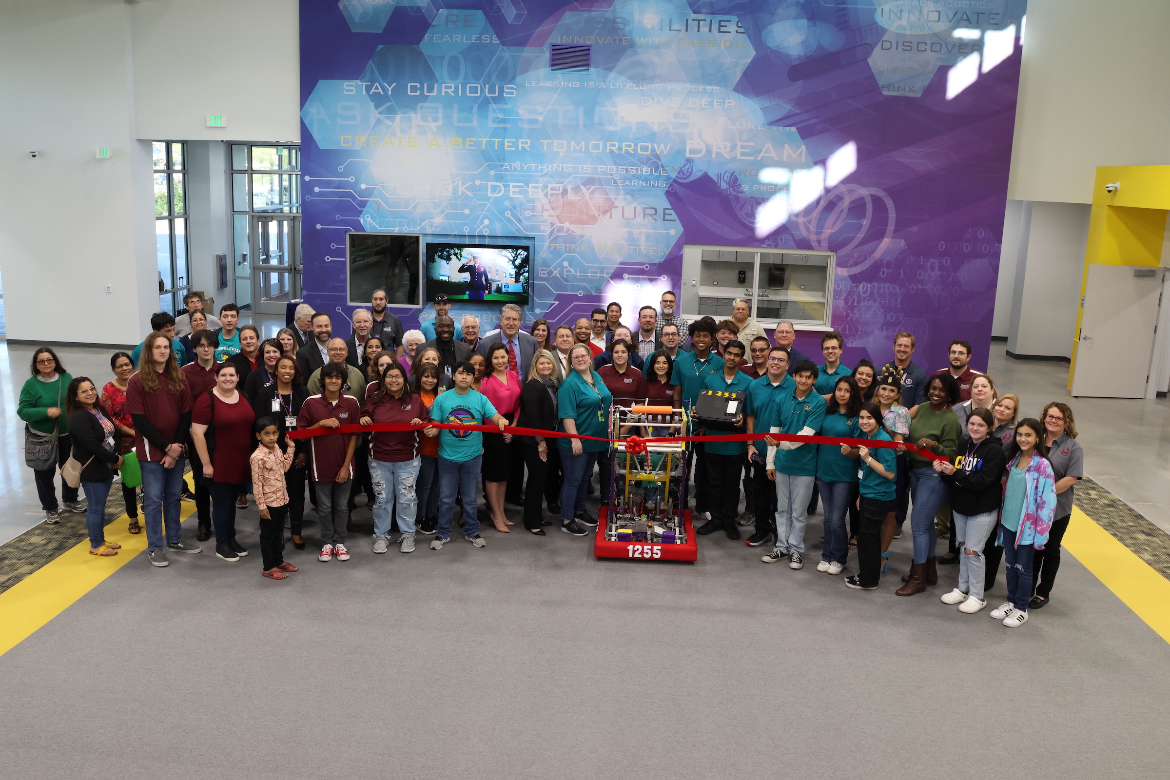 Guests pose with robot created by the Blarglefish Team during the ribbon cutting ceremony in GCCISD