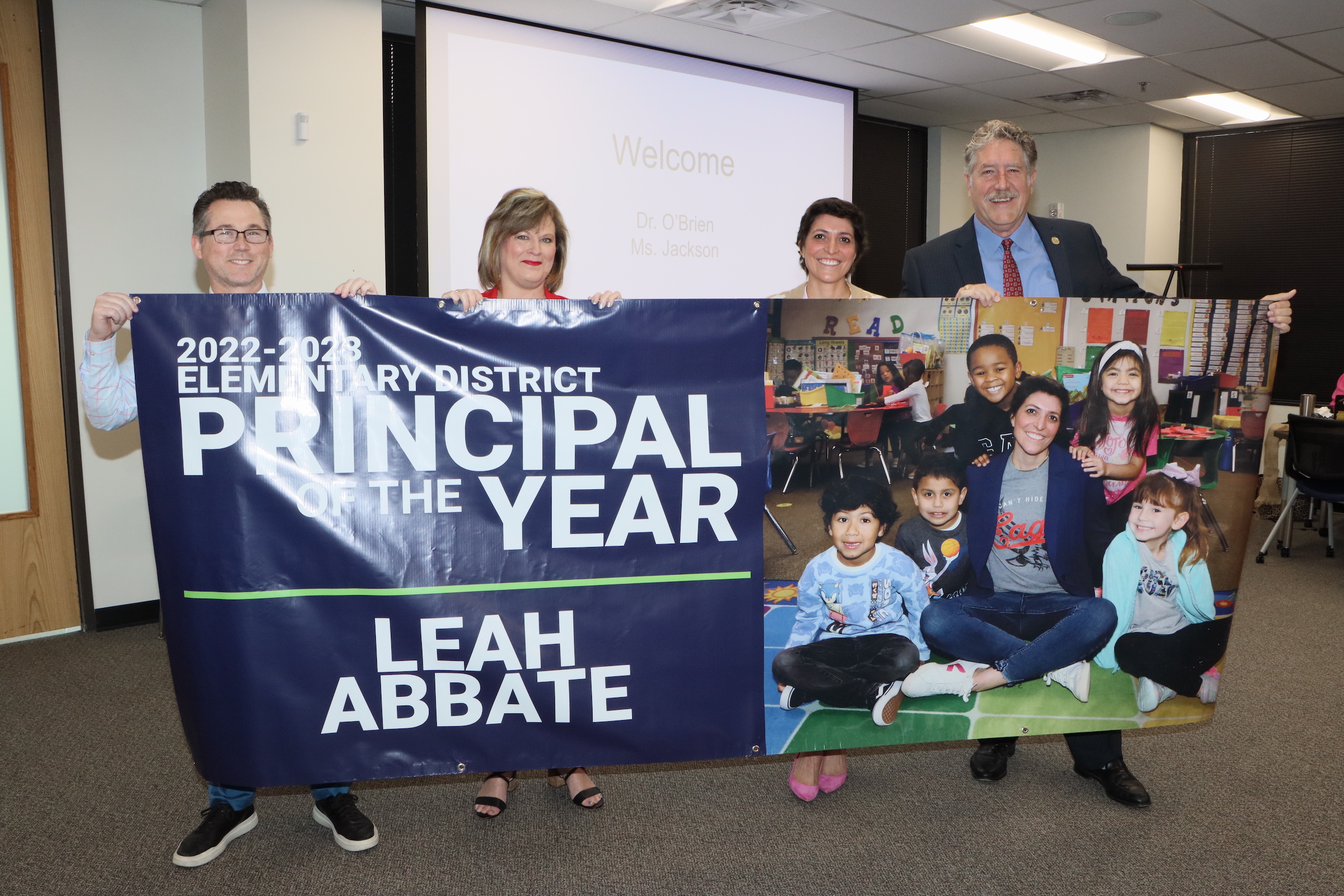Leah Abbot holds principal of the year banner with district administrators