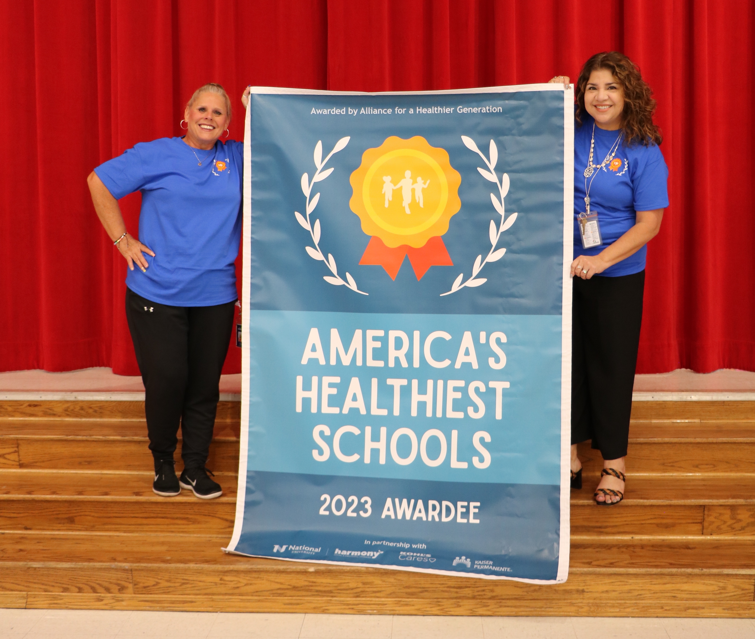 Harlem elementary poses with americas healthiest schools banner