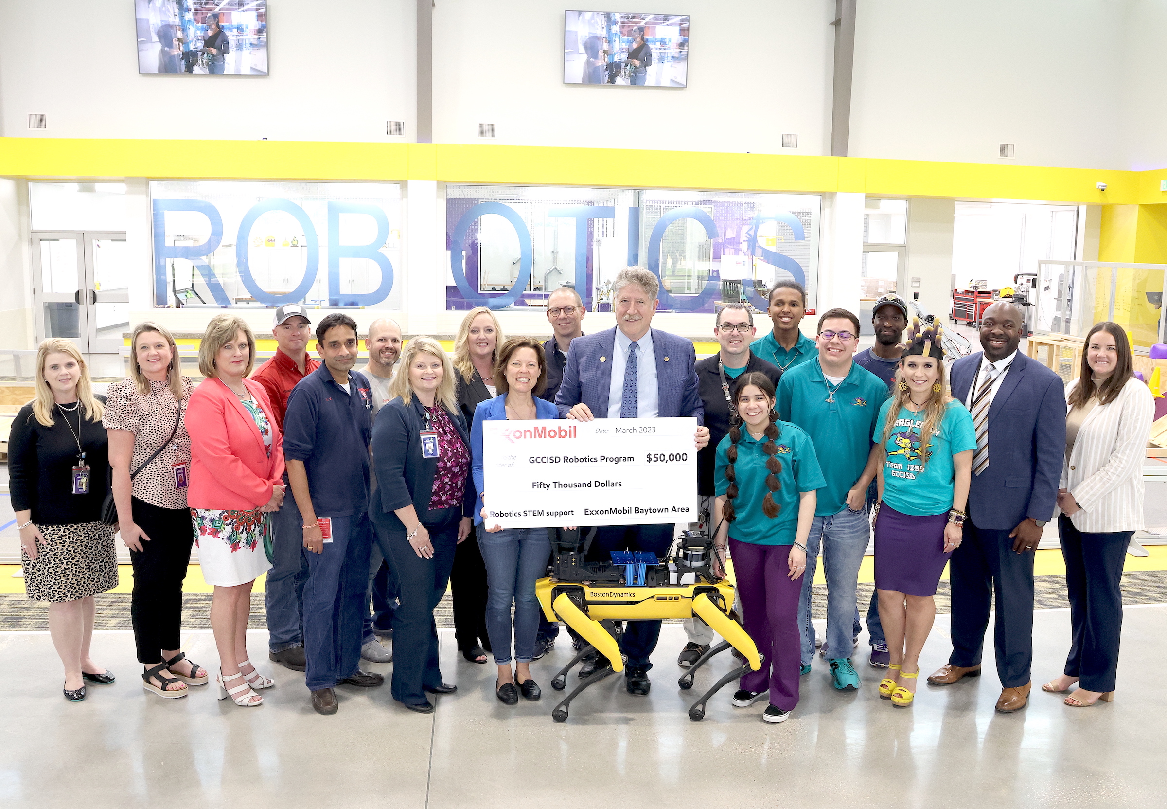 district leaders, exxon representatives, and blarglefish members pose with check and robot dog