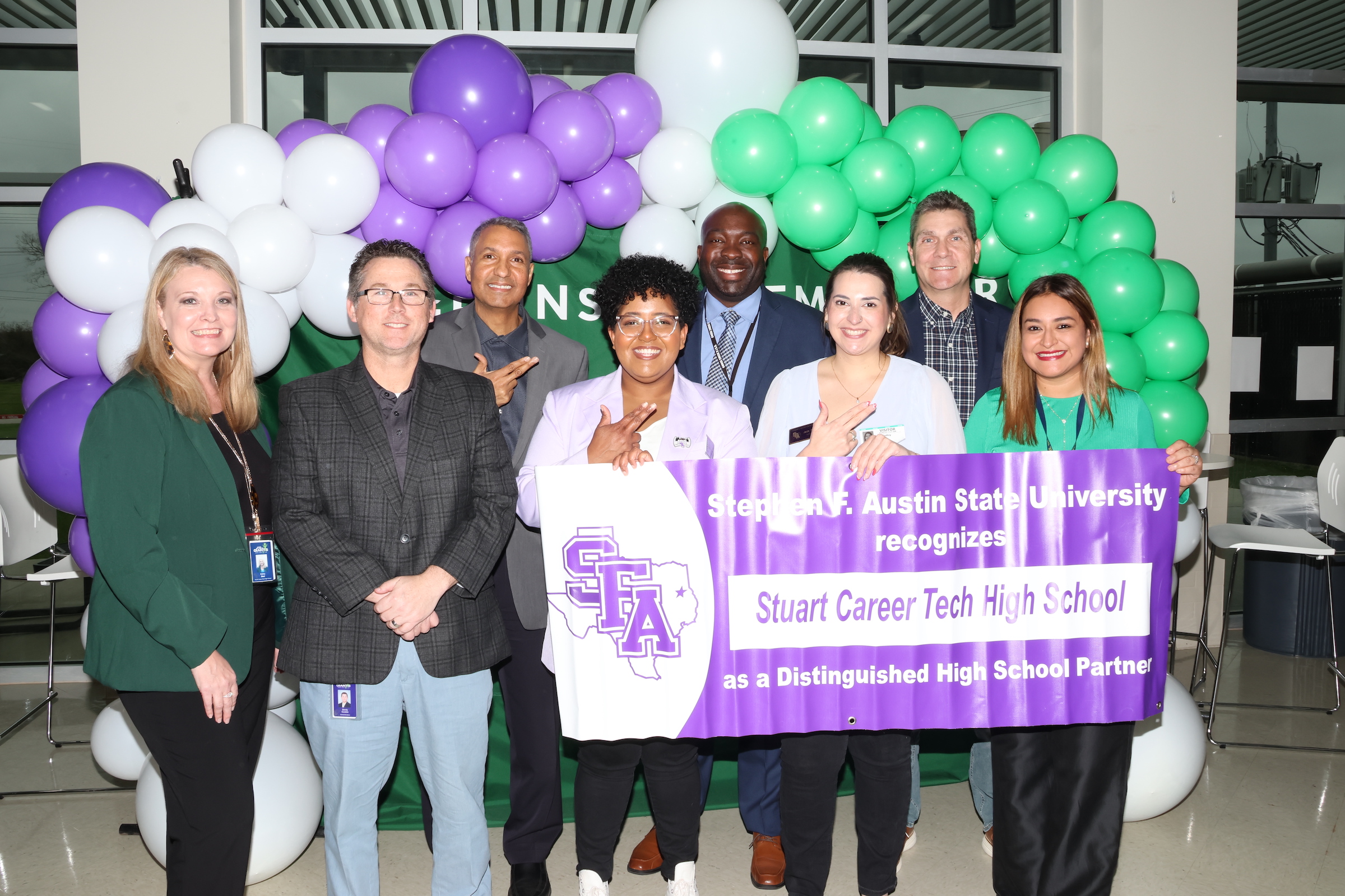 SFA University representatives pose with campus and district administration holding a partner banner